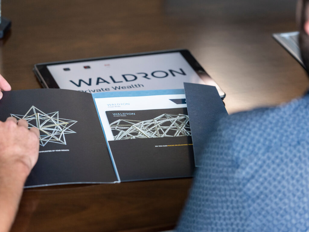 people reviewing Carronade Capital printed materials and iPad